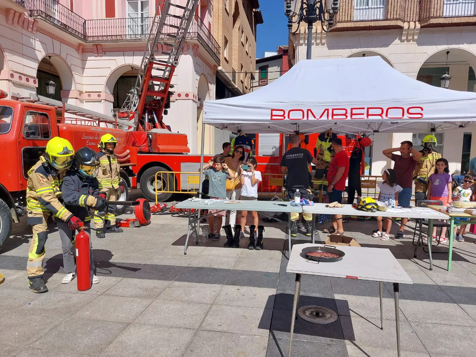 Un niño acompañado de un bombero apunta con un extintor de CO2 a una sartén en llamas para apagarla, dentro del día de los Primeros Auxilios organizado por Cruz Roja. Un niño acompañado de un bombero apunta con un extintor de CO2 a una sartén en llamas para apagarla, dentro del día de los Primeros Auxilios organizado por Cruz Roja.