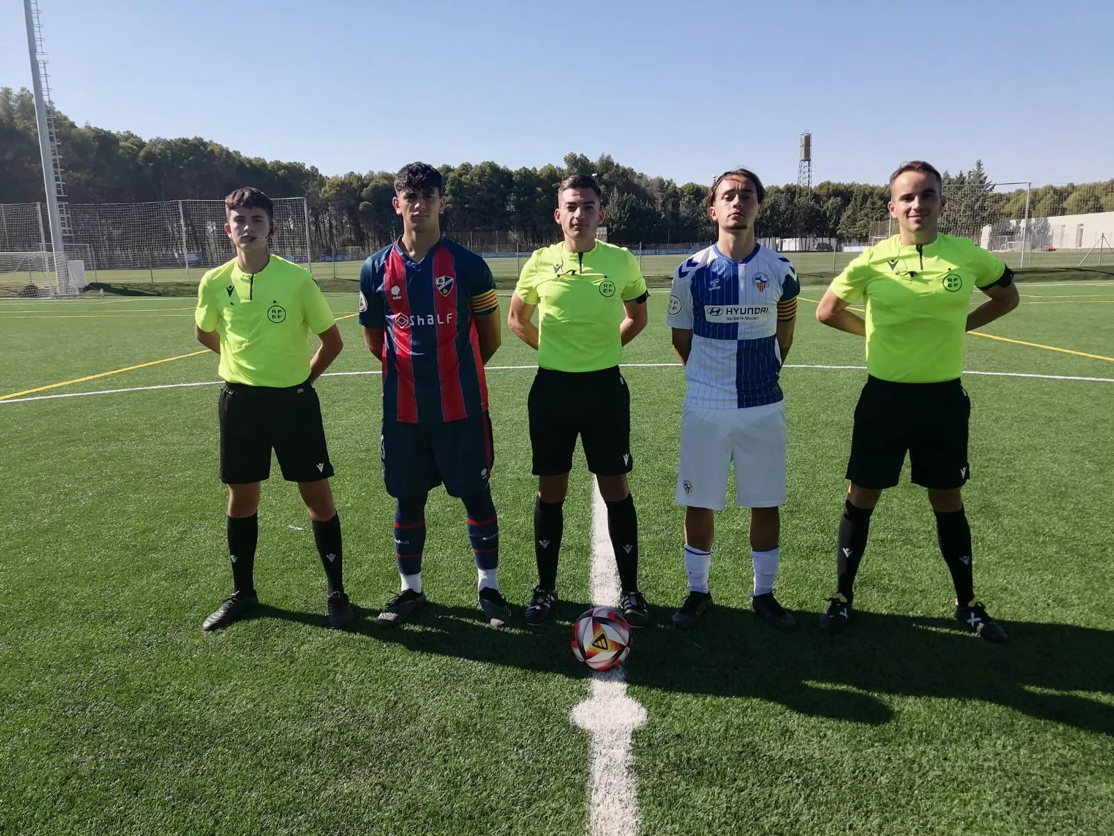 Árbitros y capitanes de Huesca y Sabadell antes del inicio del partido en la BAF.