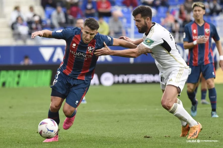 Gerard Valentín, jugador del Huesca, pelea un balón ante un jugador del Albacete. Horarios confirmados para el Huesca-Albacete y Racing Ferrol-Huesca.