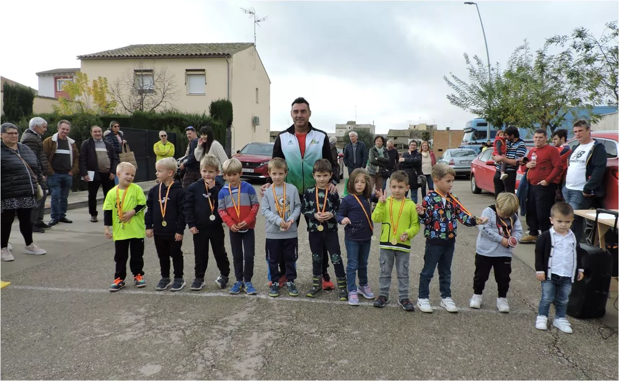 Participantes de las carreras infantiles con sus medallas, acompañados del concejal de deportes
