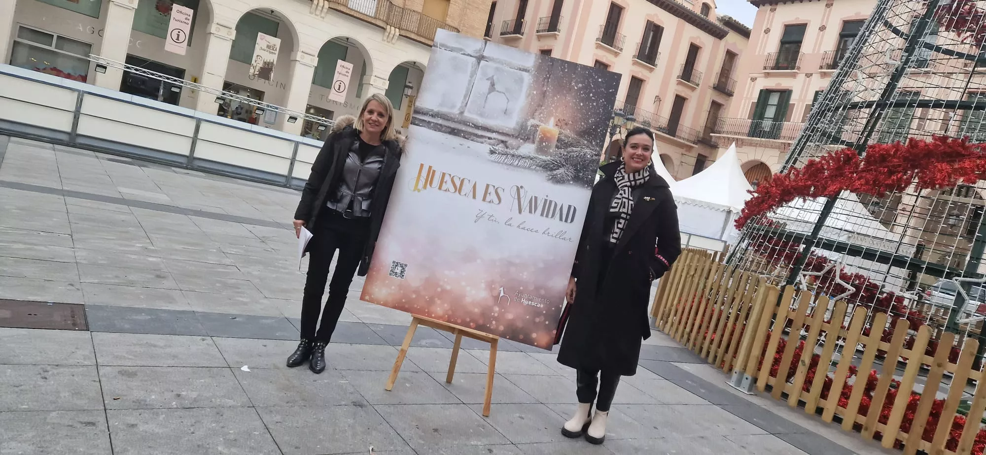 Nuria Mur y Lorena Orduna, junto al cartel de la campaña de Navidad de Huesca. Foto Myriam Martínez