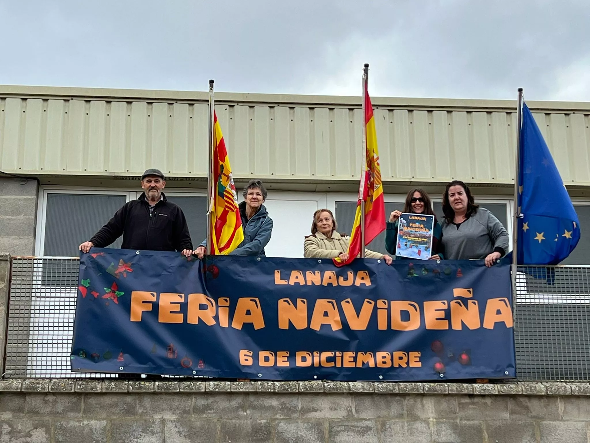 La Asociación de Mujeres de Lanaja con el cartel de la Feria Navideña.