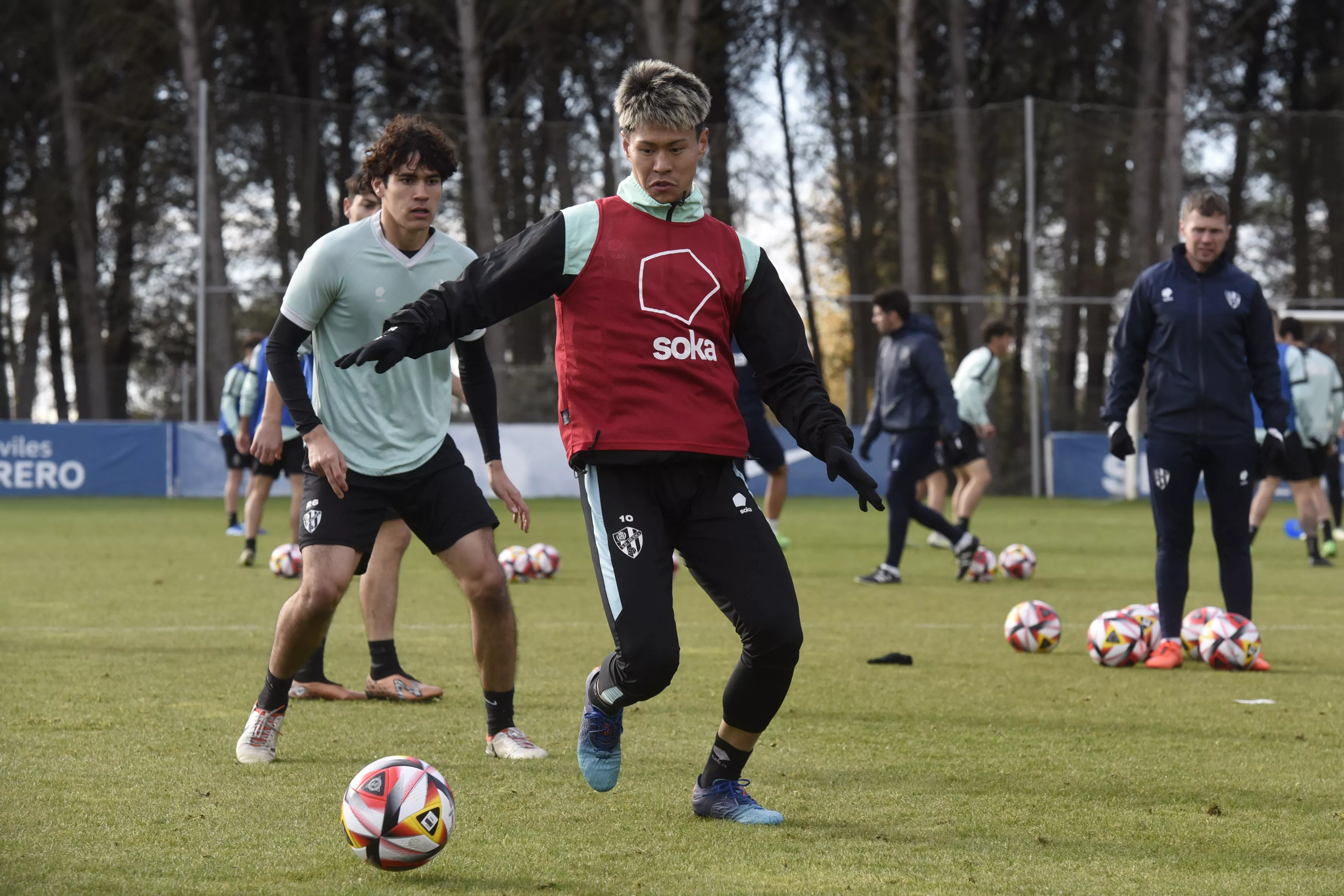 Kento, en primer plano, protege un balón en el entrenamiento de este lunes del Huesca en la BAF.