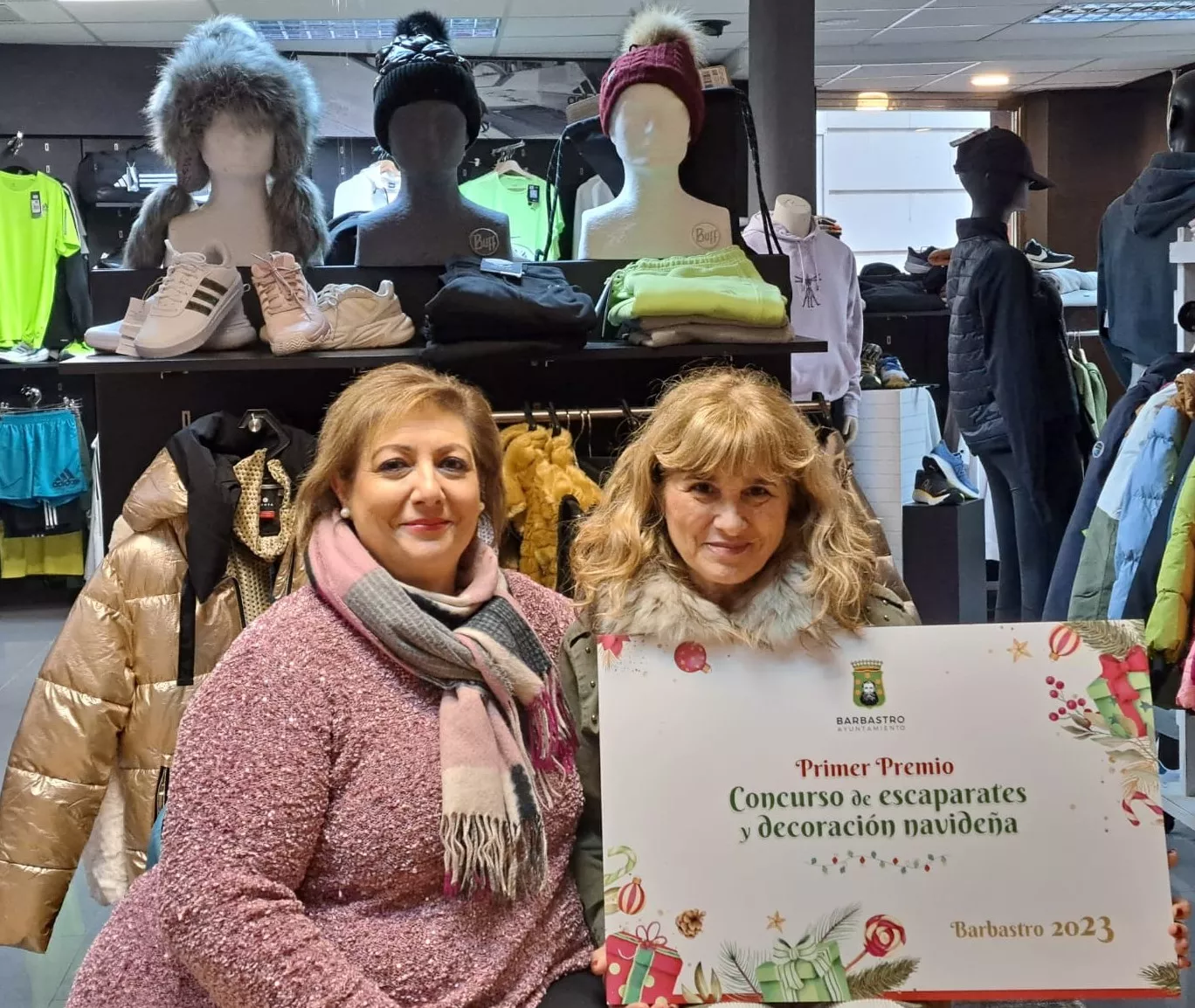 La concejala de Desarrollo y la responsable de Chaca Sport muestran el diploma del primer premio del certamen de escaparates.