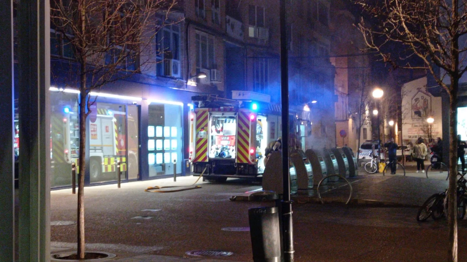 Un camión de bomberos apaga los contenedores en la plaza Ramón y Alberto Gil Novales de Huesca