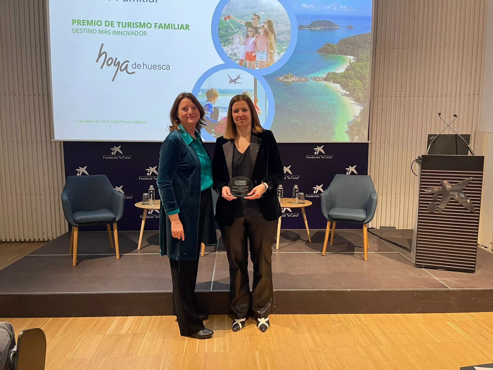 La presidenta comarcal Mónica Soler, a la derecha, recoge el Premio de Turismo Familiar como destino innovador.