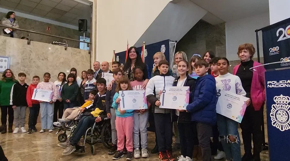 Alumnos premiados en el concurso de dibujo de la Policía Nacional junto con las autoridades que han presidido el acto. 
