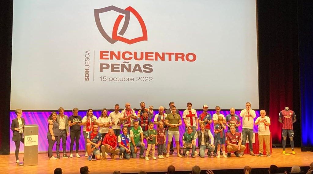 Los representantes de las Peñas del Huesca recogen el galardón sobre el escenario del Palacio de Congresos. Foto: A. Mora
