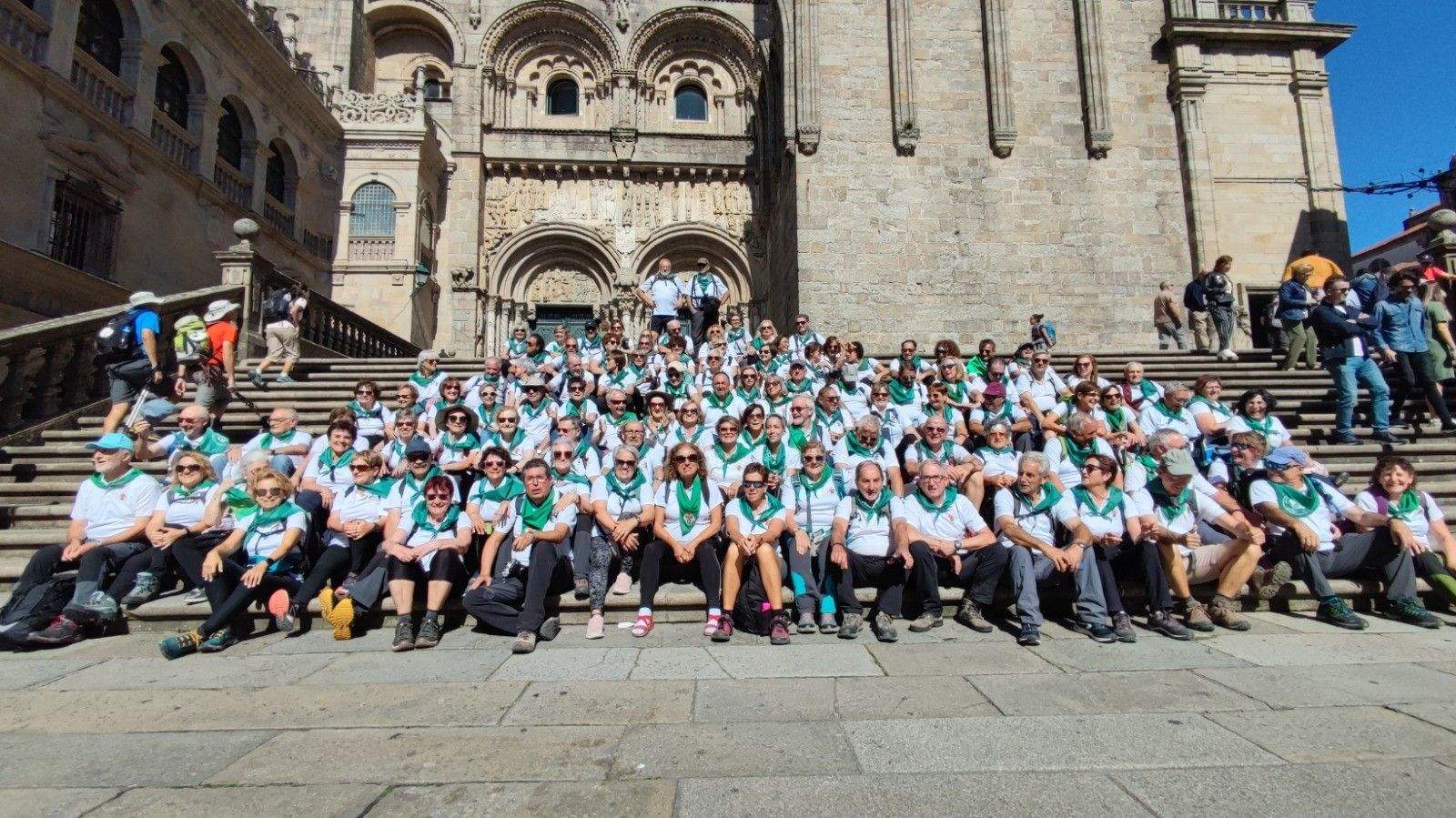 Peregrinos oscenses, de blanco y verde, ante el templo compostelano