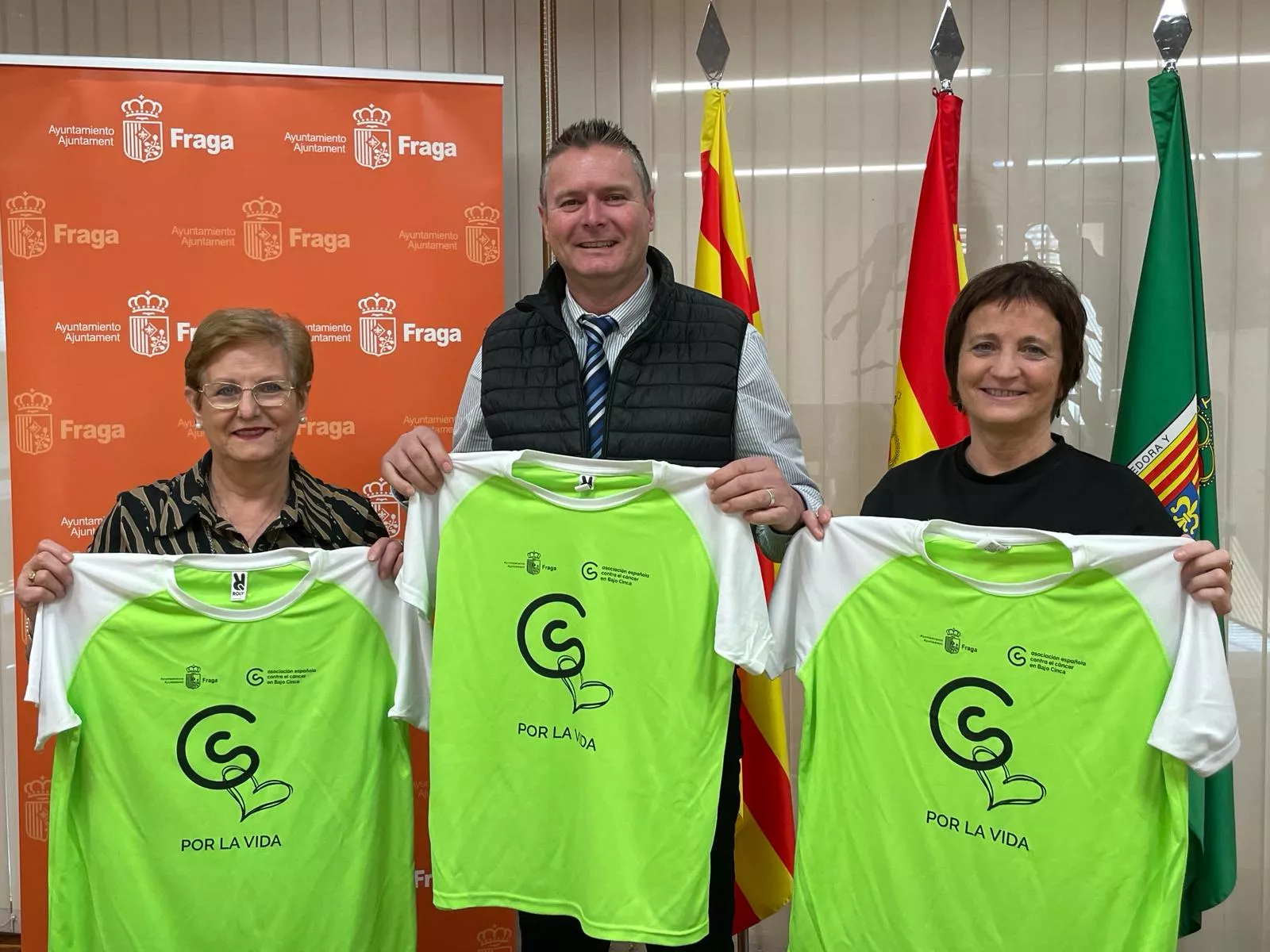 Mari Carmen Márquez, Ignacio Gramún y Fina Escándil con las camisetas verdes que vestirán los participantes de la carrera.