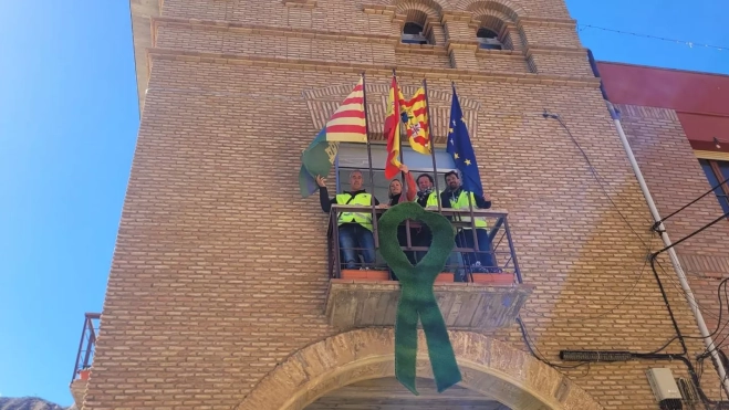 Los representantes de HEGA en el balcón del ayuntamiento de Alcolea de Cinca con un crespón verde