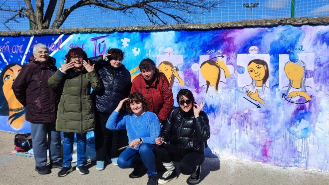 Mujeres ASZA frente a signos en mural Mujeres ASZA frente a signos en mural