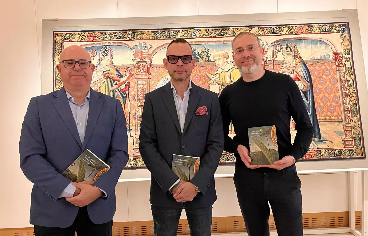 Fernando Sarriá, Javier Olloqui  y Eduardo Barba, ante el Tapiz de la Virgen y San Vicente, en la presentación de la "Guía botánica del Museo de Huesca".