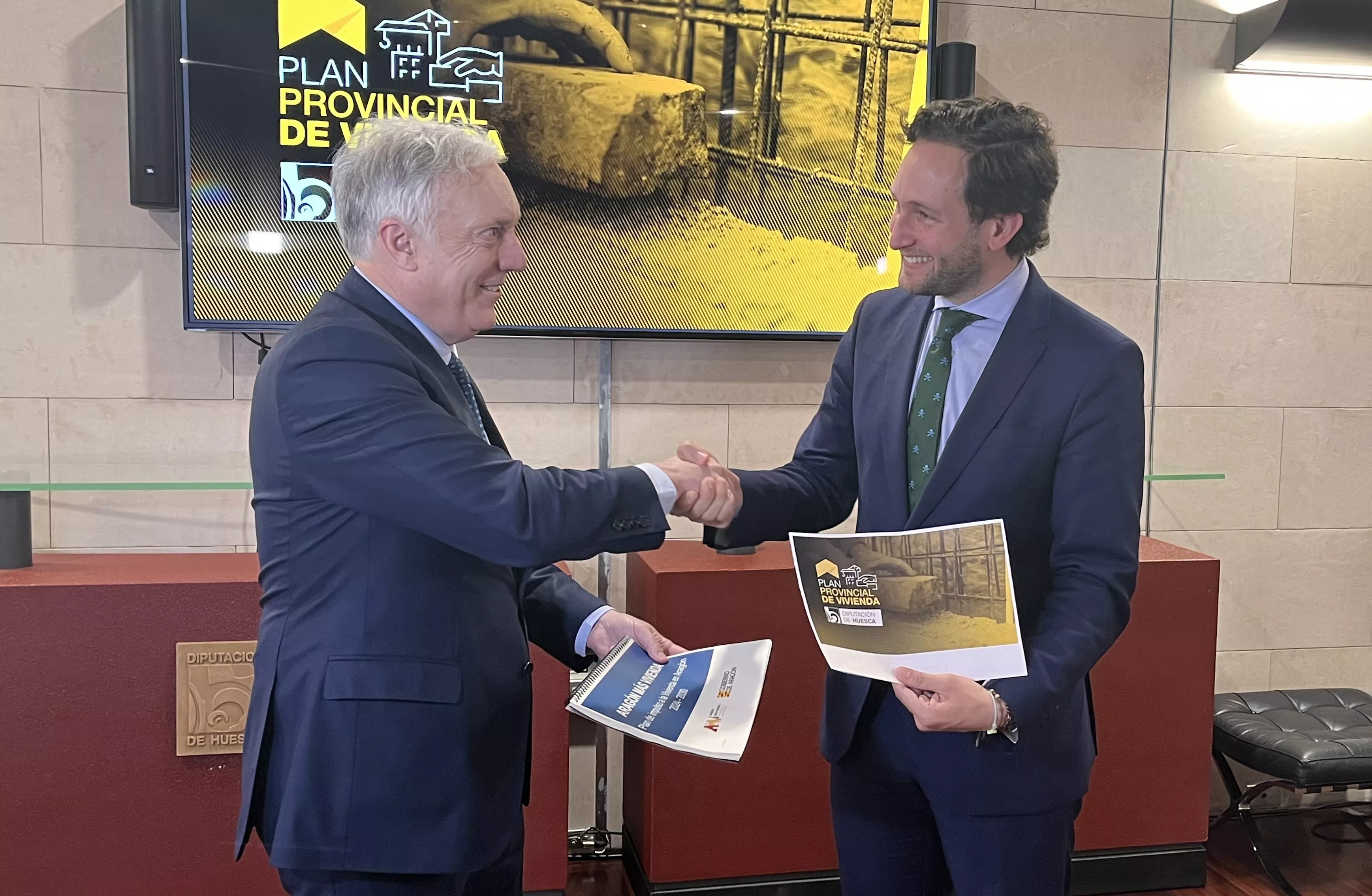 Octavio López e Isaac Claver se saludan mientras sostienen su respectivos planes de vivienda. Octavio López e Isaac Claver se saludan mientras sostienen su respectivos planes de vivienda.