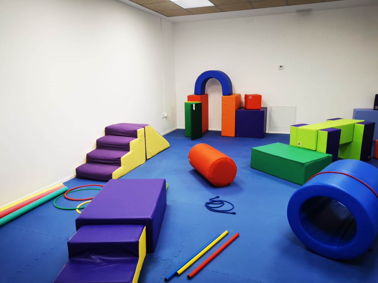Sala adaptada en el pabellón municipal para niños de 0 a 6 años con colchonetas y bloques de espuma blanda