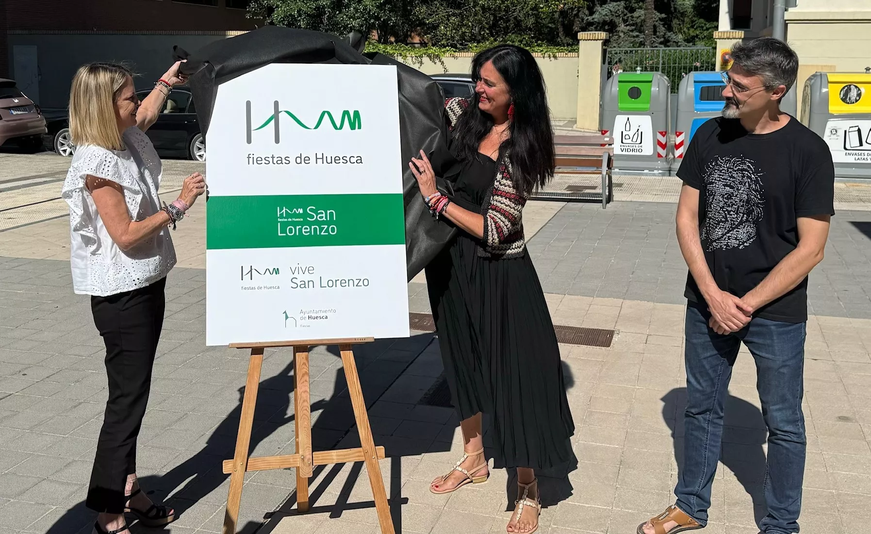 Nuria Mur y Lorena Orduna descubren la imagen de marca de las fiestas, junto a su autor, David Adiego.