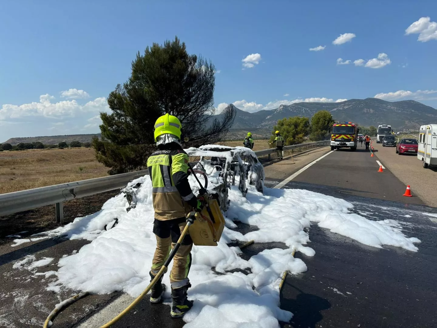 Bomberos de Huesca durante su intervención para sofocar el fuego del vehículo.