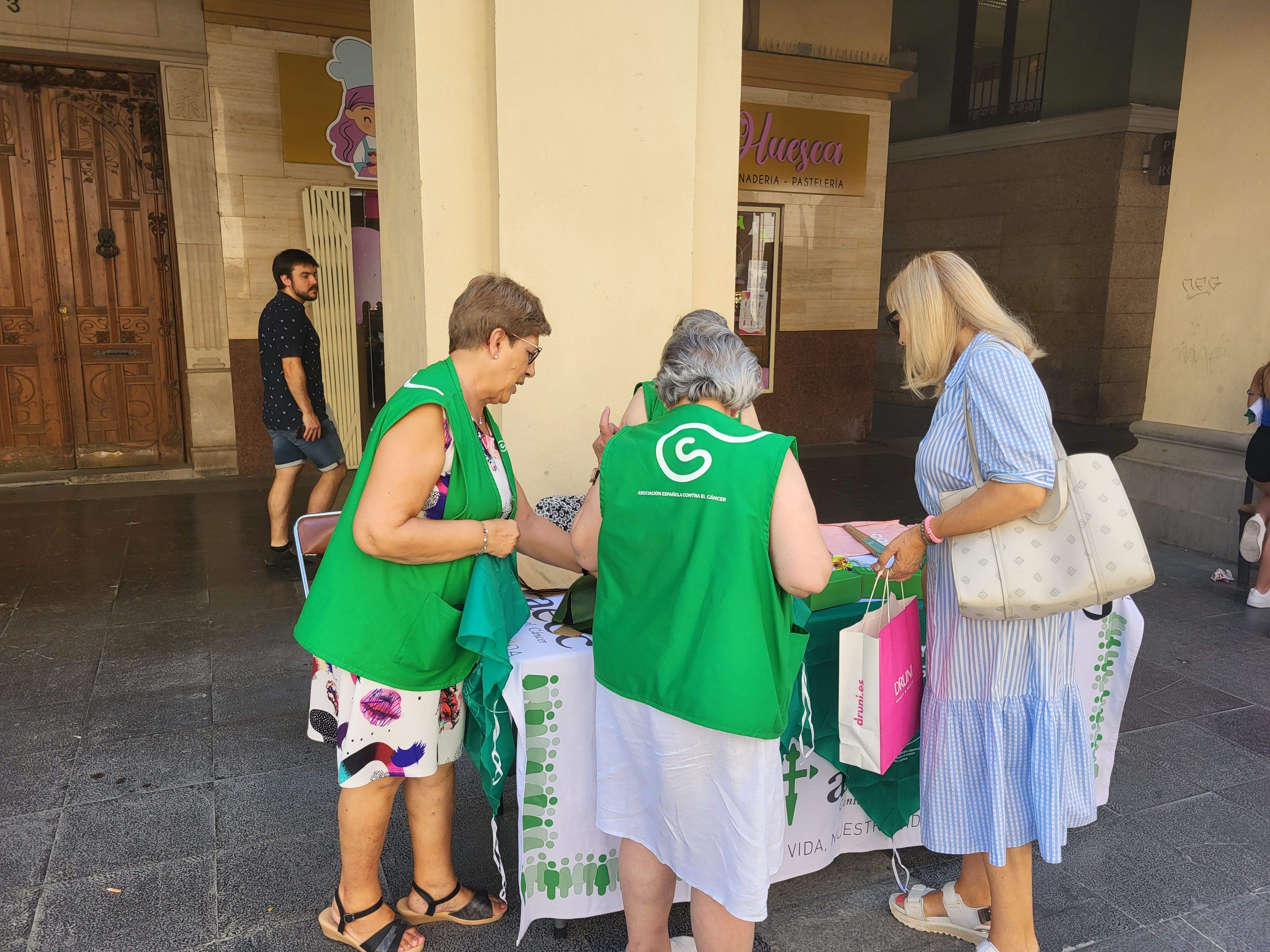 Voluntarias de la Asociación Española contra el Cáncer de Huesca venden pañoletas para San Lorenzo