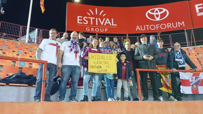 Afición del Huesca con el cartel preparado por Pilar Cereza. Entre ellos, miembros de la Peña de la SD Huesca en Barcelona Afición del Huesca con el cartel preparado por Pilar Cereza. Entre ellos, miembros de la Peña de la SD Huesca en Barcelona