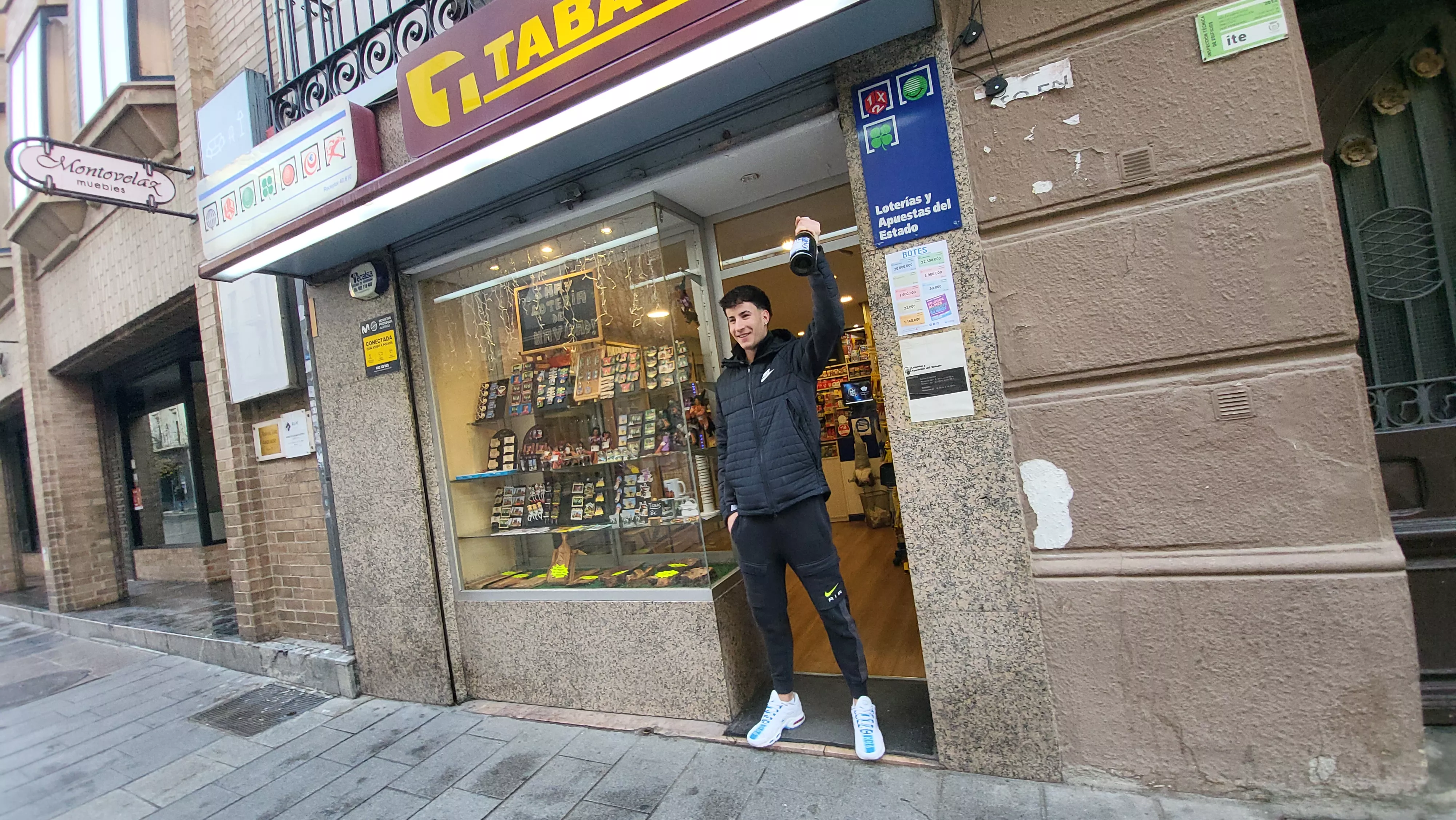 Adrián Izquierdo celebra el premio repartido ante la puerta del estanco con el cava en la mano. Adrián Izquierdo celebra el premio repartido ante la puerta del estanco con el cava en la mano.