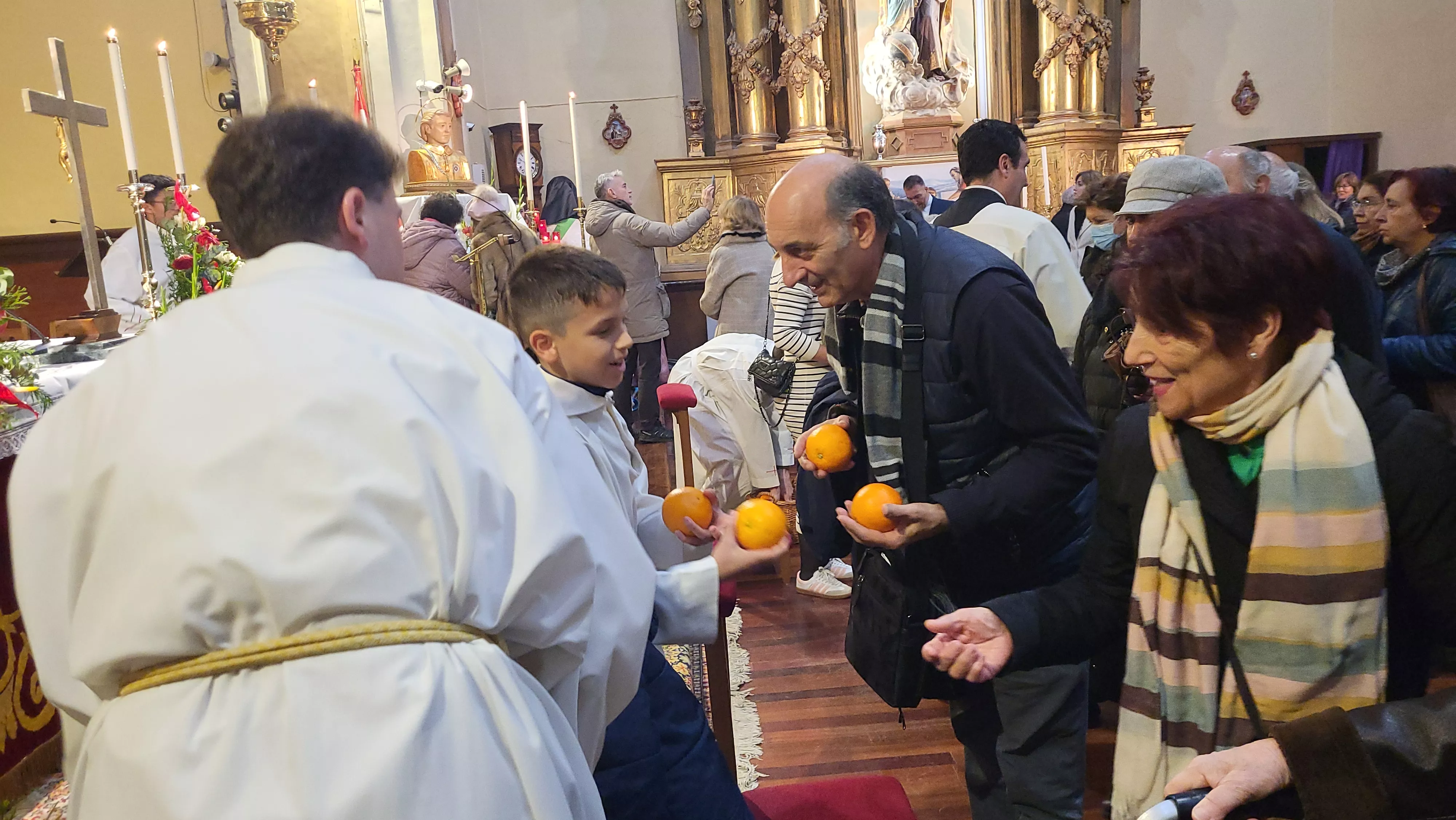 Tradicional reparto de naranjas al término de la misa. Foto Mercedes Manterola