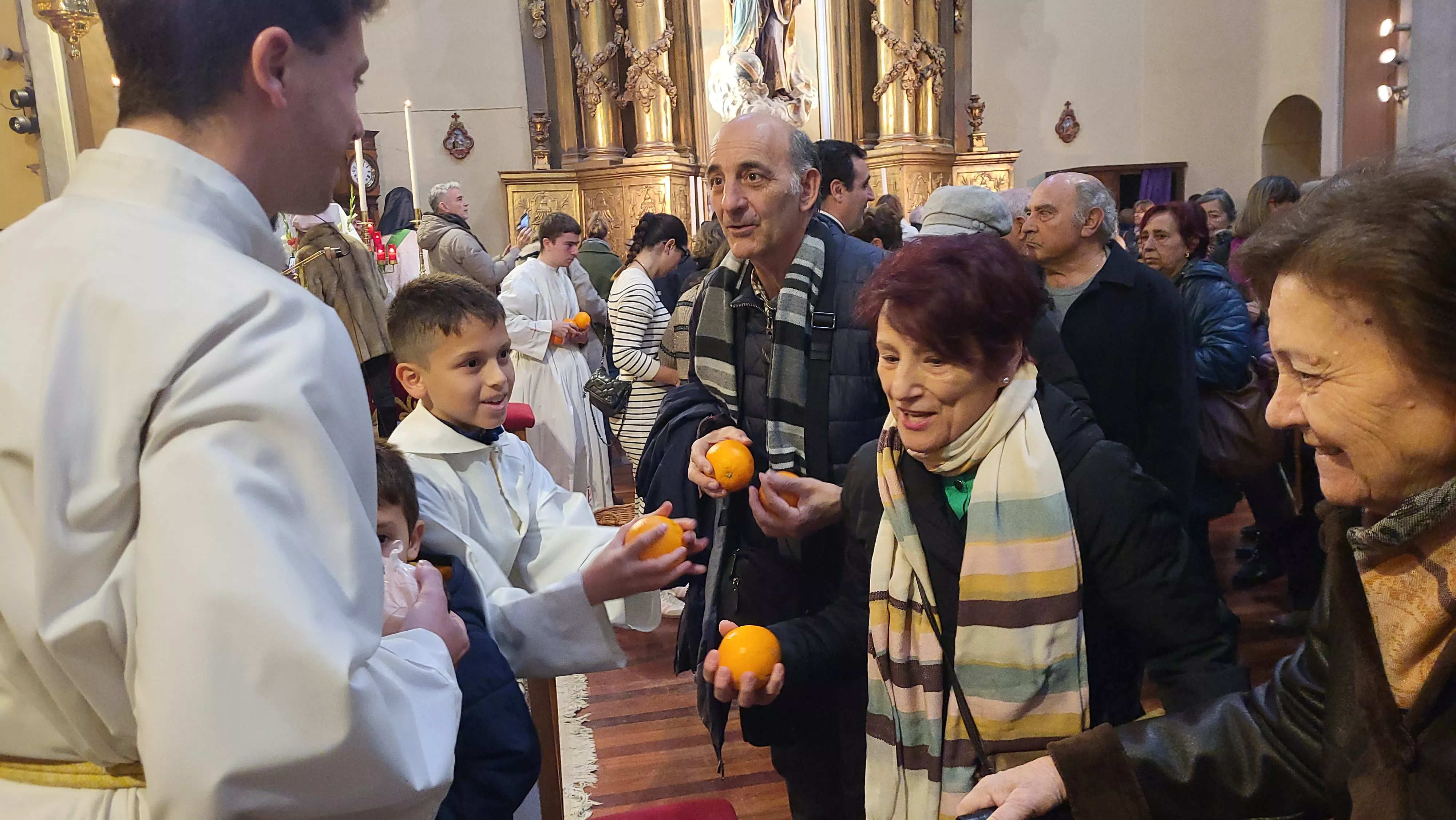 Tradicional reparto de naranjas al término de la misa. Foto Mercedes Manterola