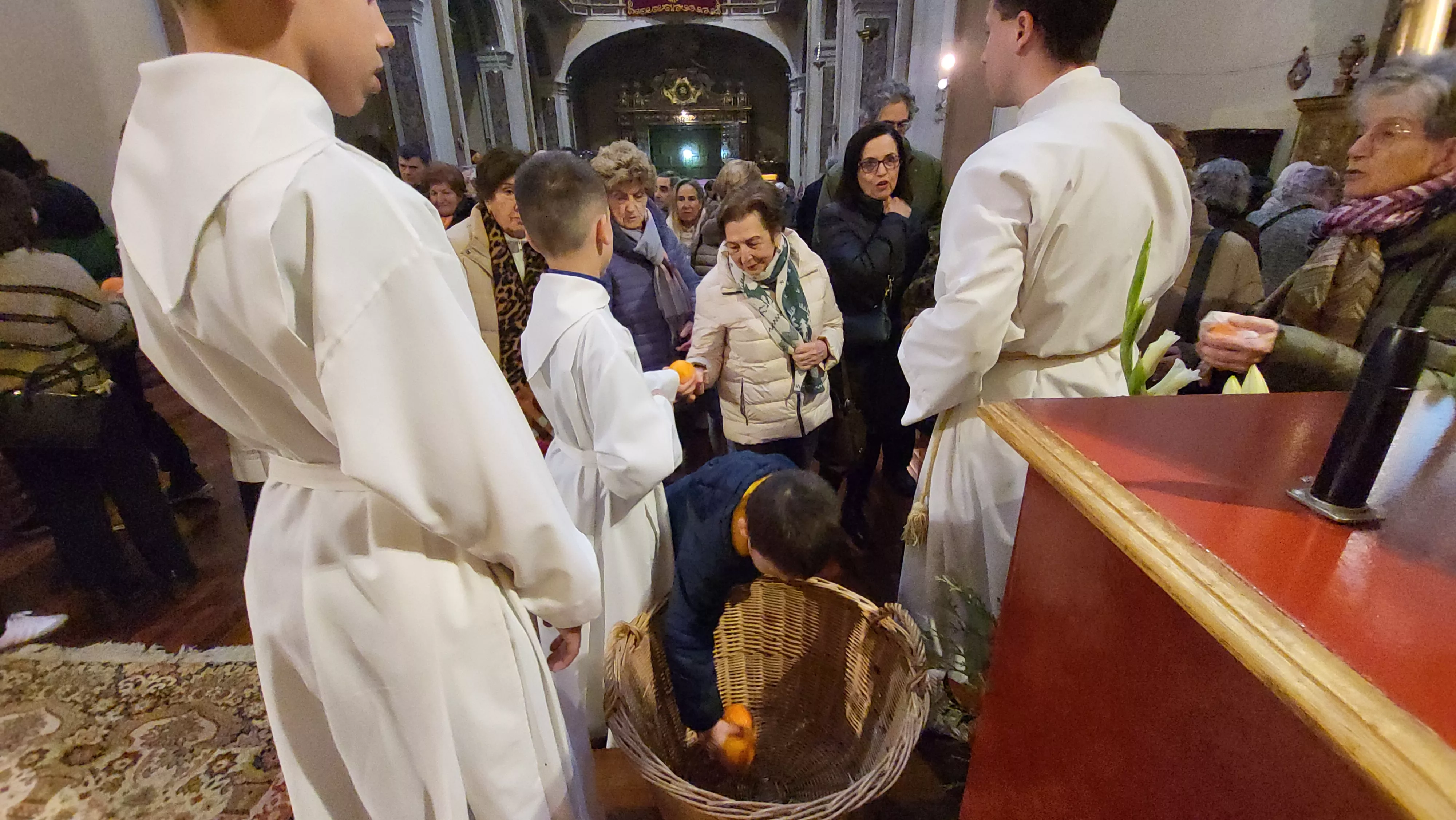 Tradicional reparto de naranjas al término de la misa. Foto Mercedes Manterola