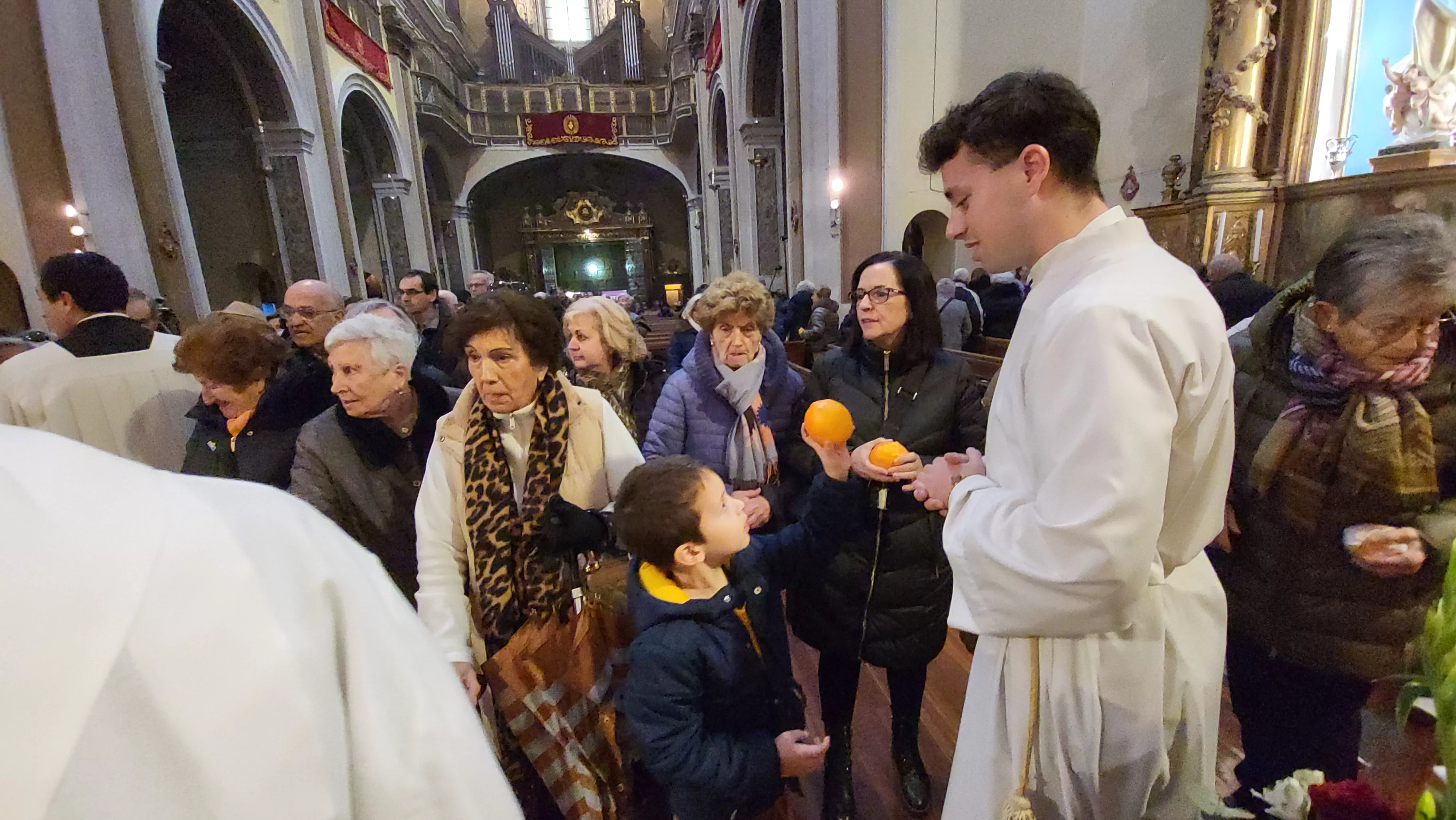 Tradicional reparto de naranjas al término de la misa. Foto Mercedes Manterola