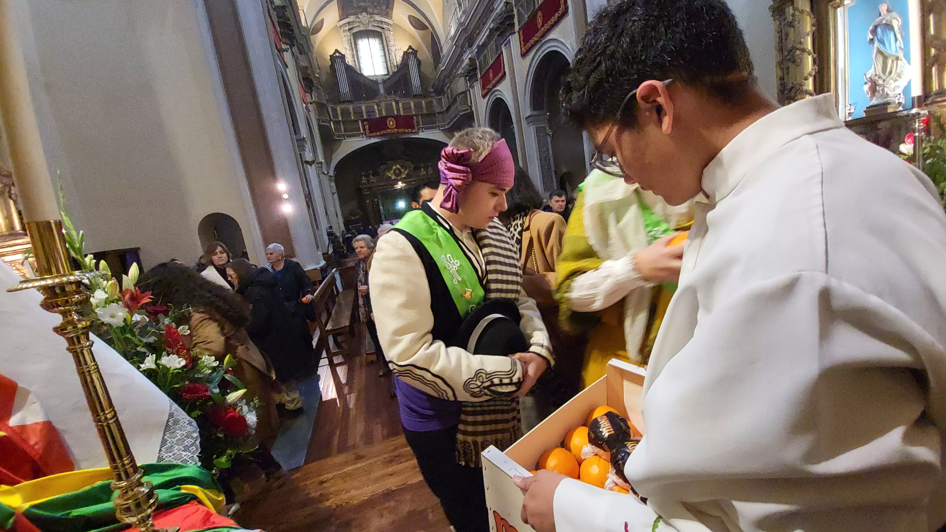 Tradicional reparto de naranjas al término de la misa. Foto Mercedes Manterola