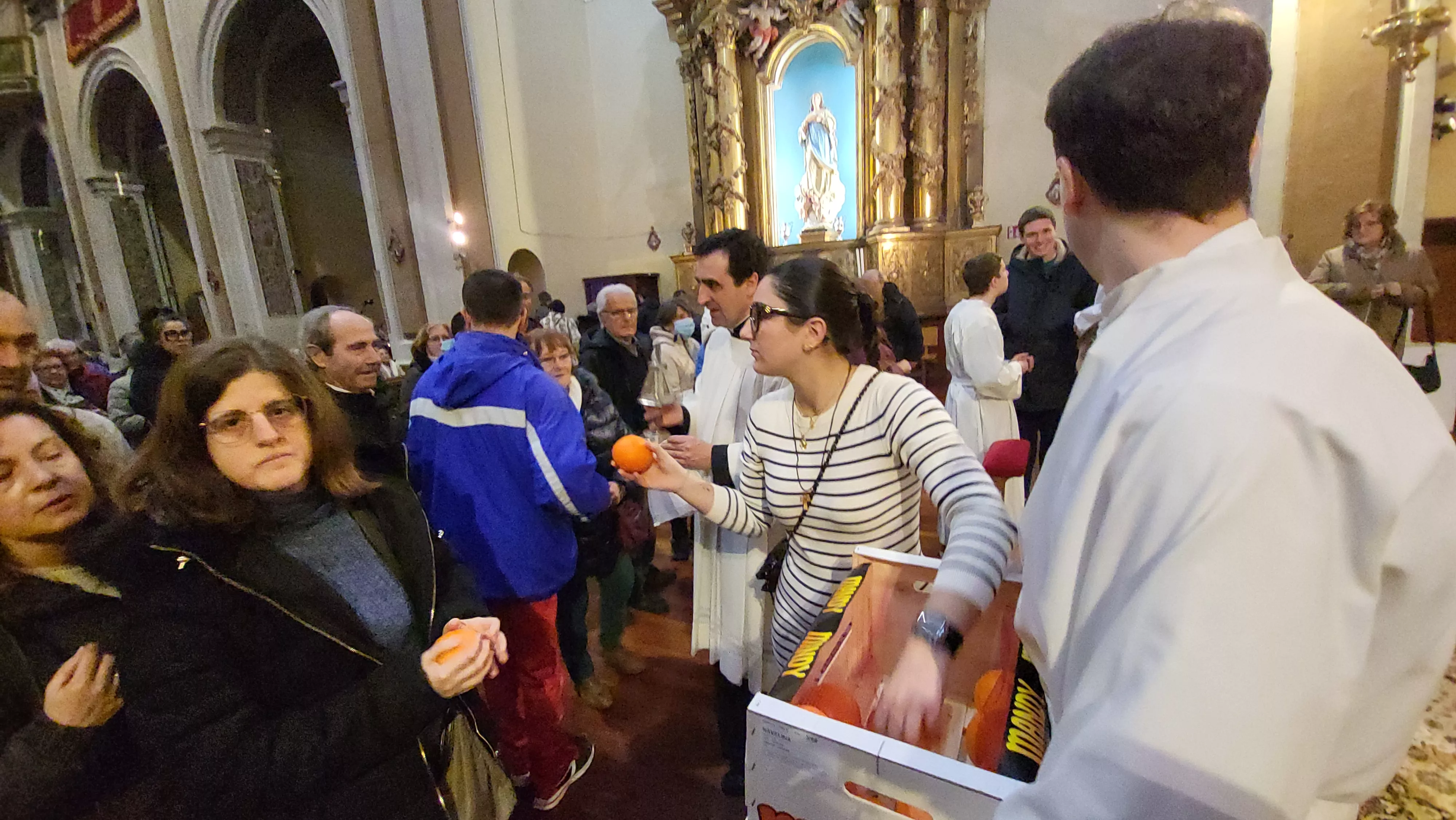 Tradicional reparto de naranjas al término de la misa. Foto Mercedes Manterola