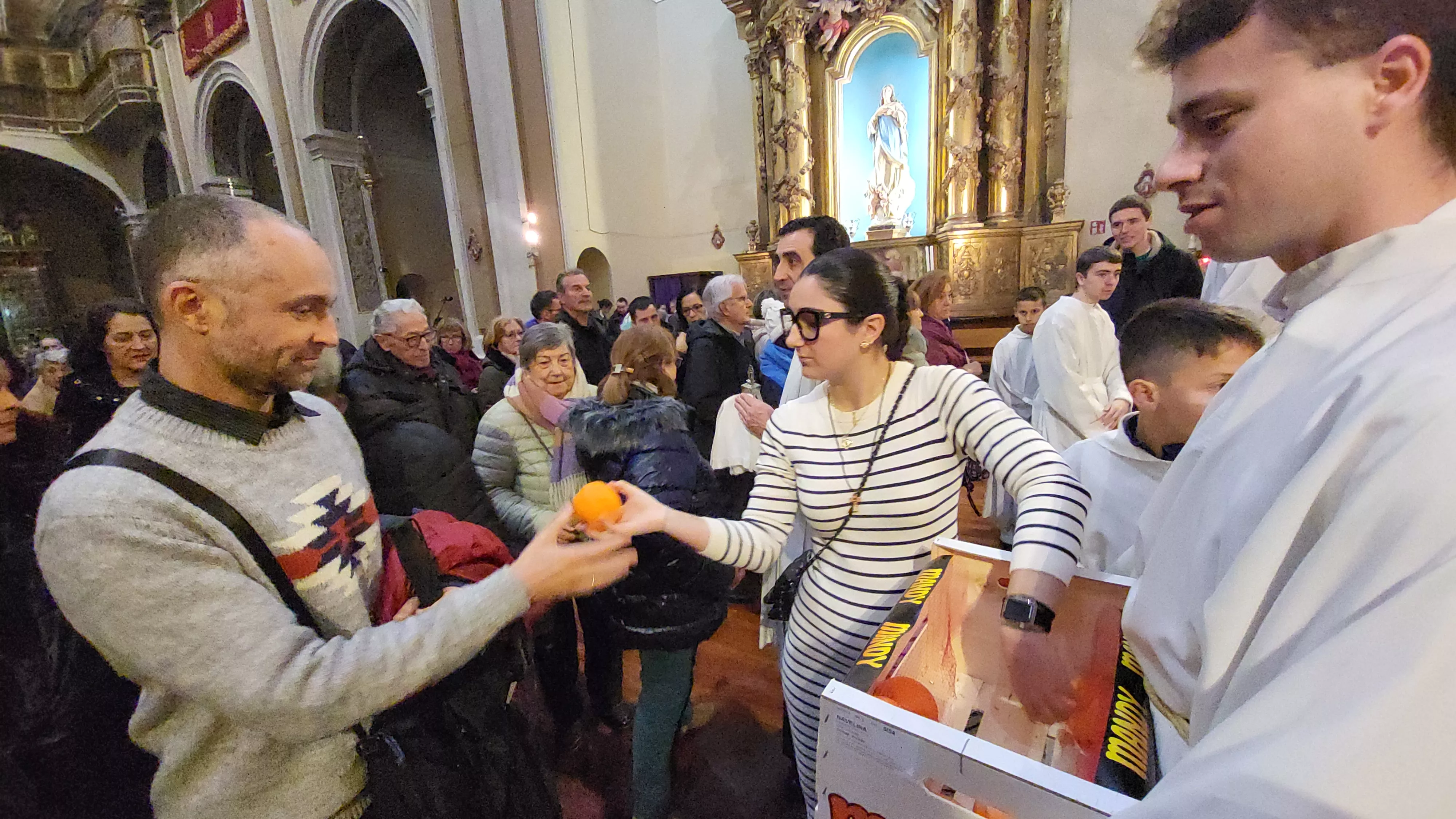 Tradicional reparto de naranjas al término de la misa. Foto Mercedes Manterola