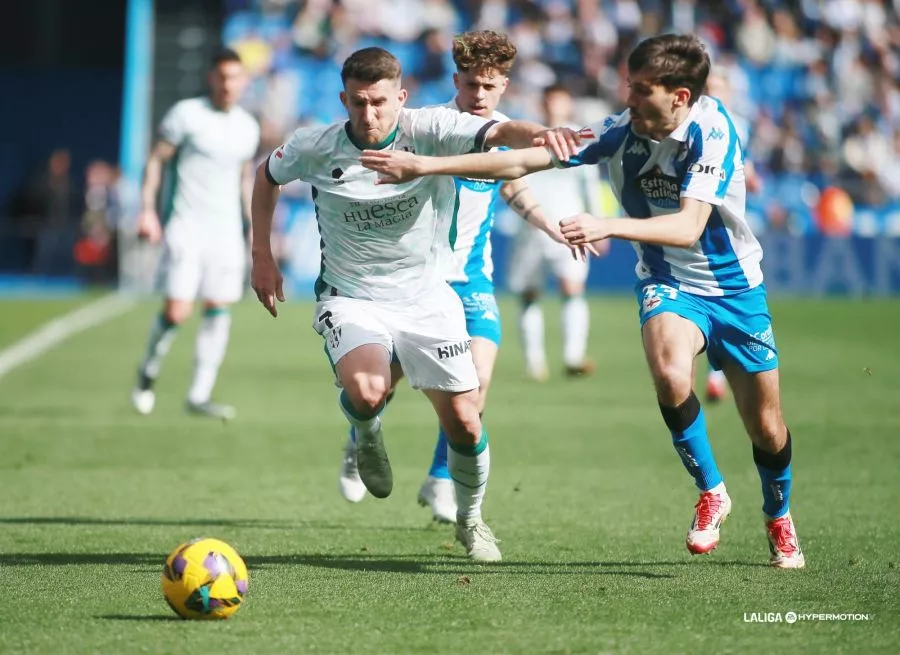 Valentín, jugador del Huesca, pelea un balón ante un rival del Deportivo. Foto: LaLiga