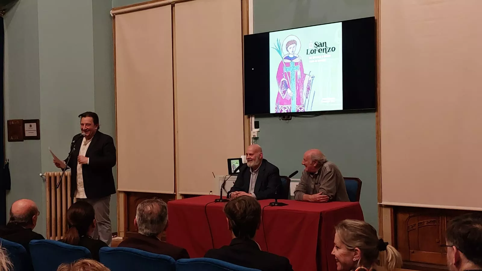 Javier Monsón y Marcelino Sesé debajo de la portada de San Lorenzo: de Huesca a Roma para el mundo, y, a su derecha, Toño Julve