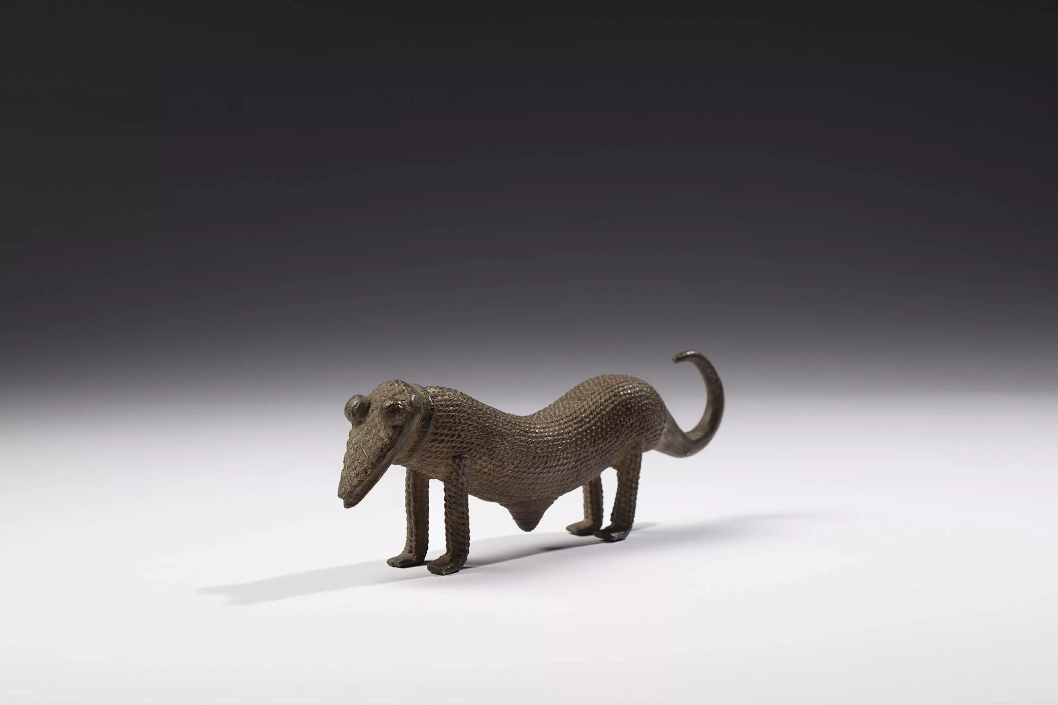 Probable representación de un pangolín. Cultura gan. Burkina Faso. Siglos XIX - XX. Bronce con pátina ligera de oxidación,  6 x 19 x 3,5 cm.