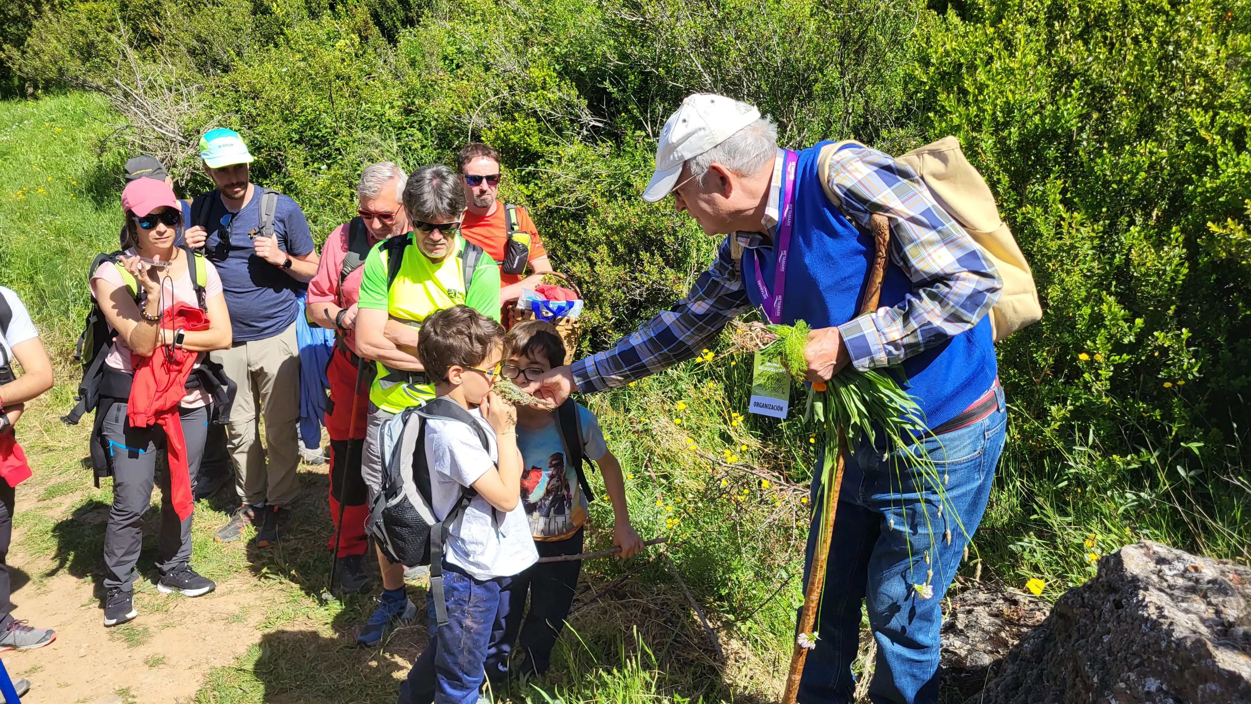 Dos niños huelen la Ruda de manos de Manuel Roncero en el Caminito Medicinal de Agüero