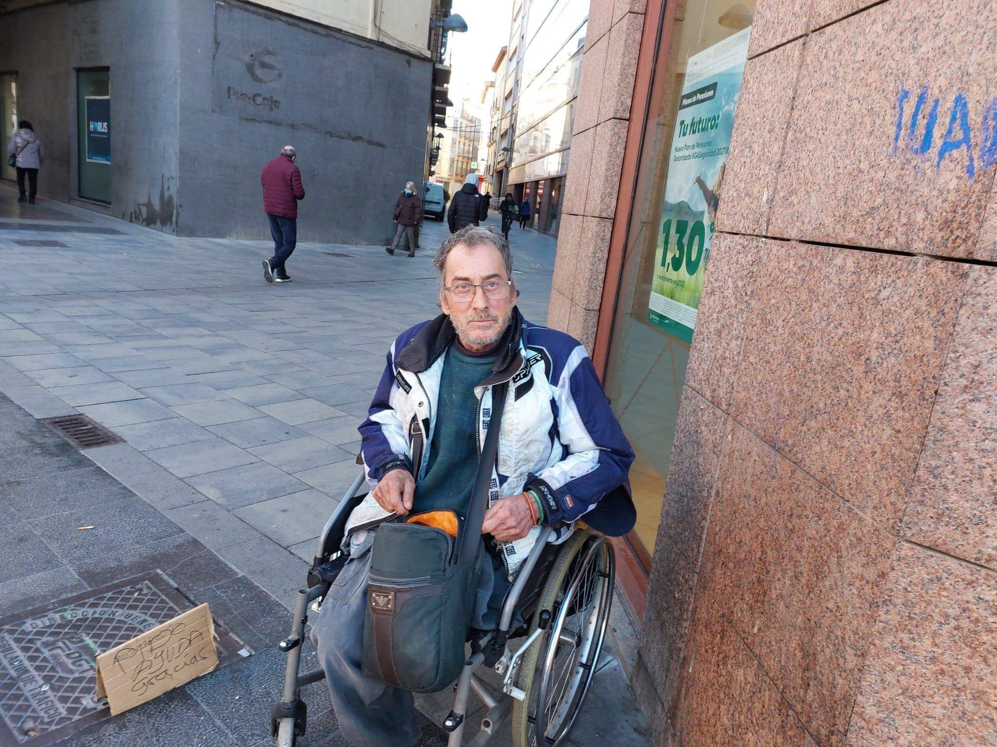 Juan, en su 'centro de trabajo', debajo de un cartel sobre planes de pensiones y detrás la vieja oficina de otra caja.