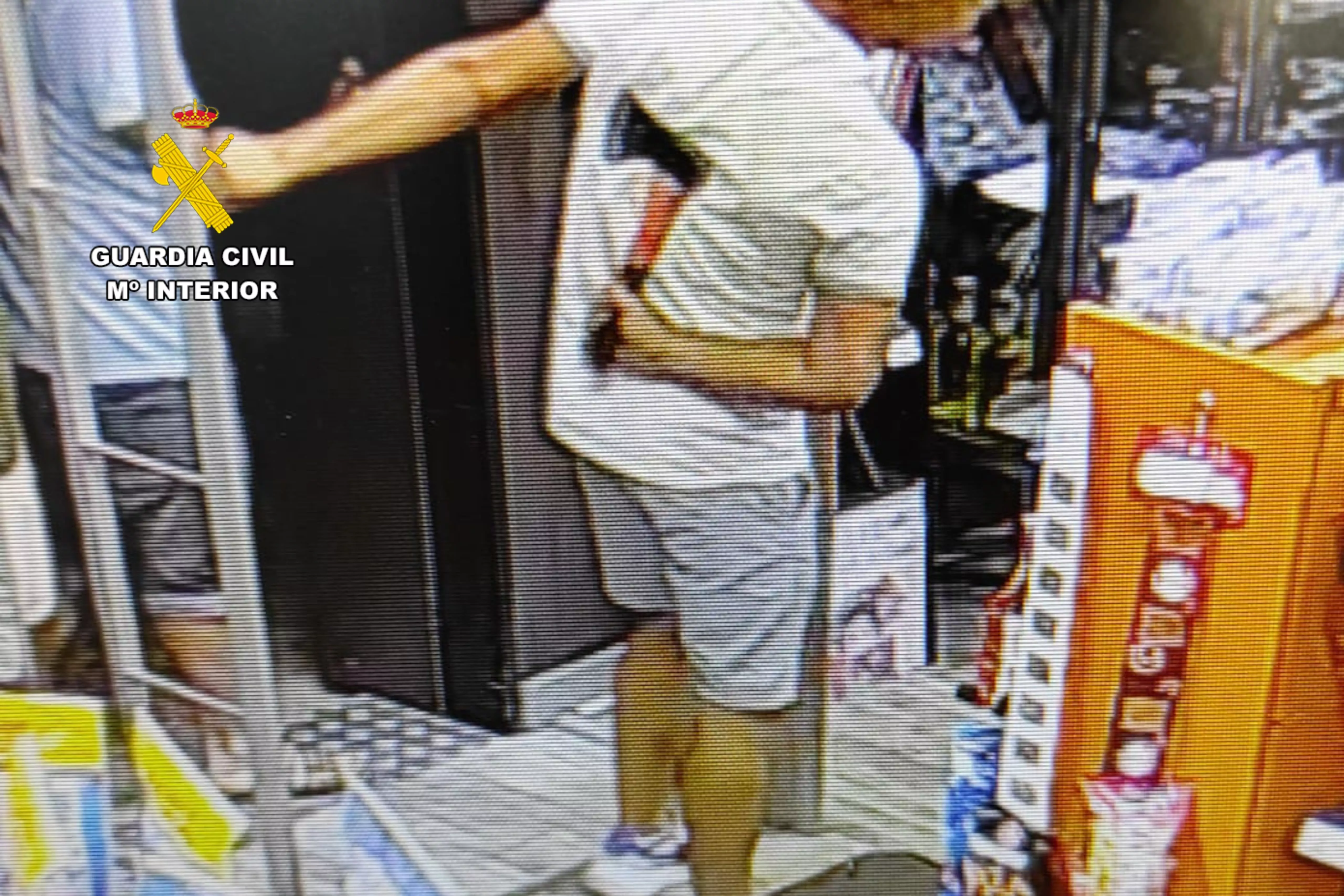 Uno de los individuos entrando en un establecimiento con un hacha oculta en su espalda