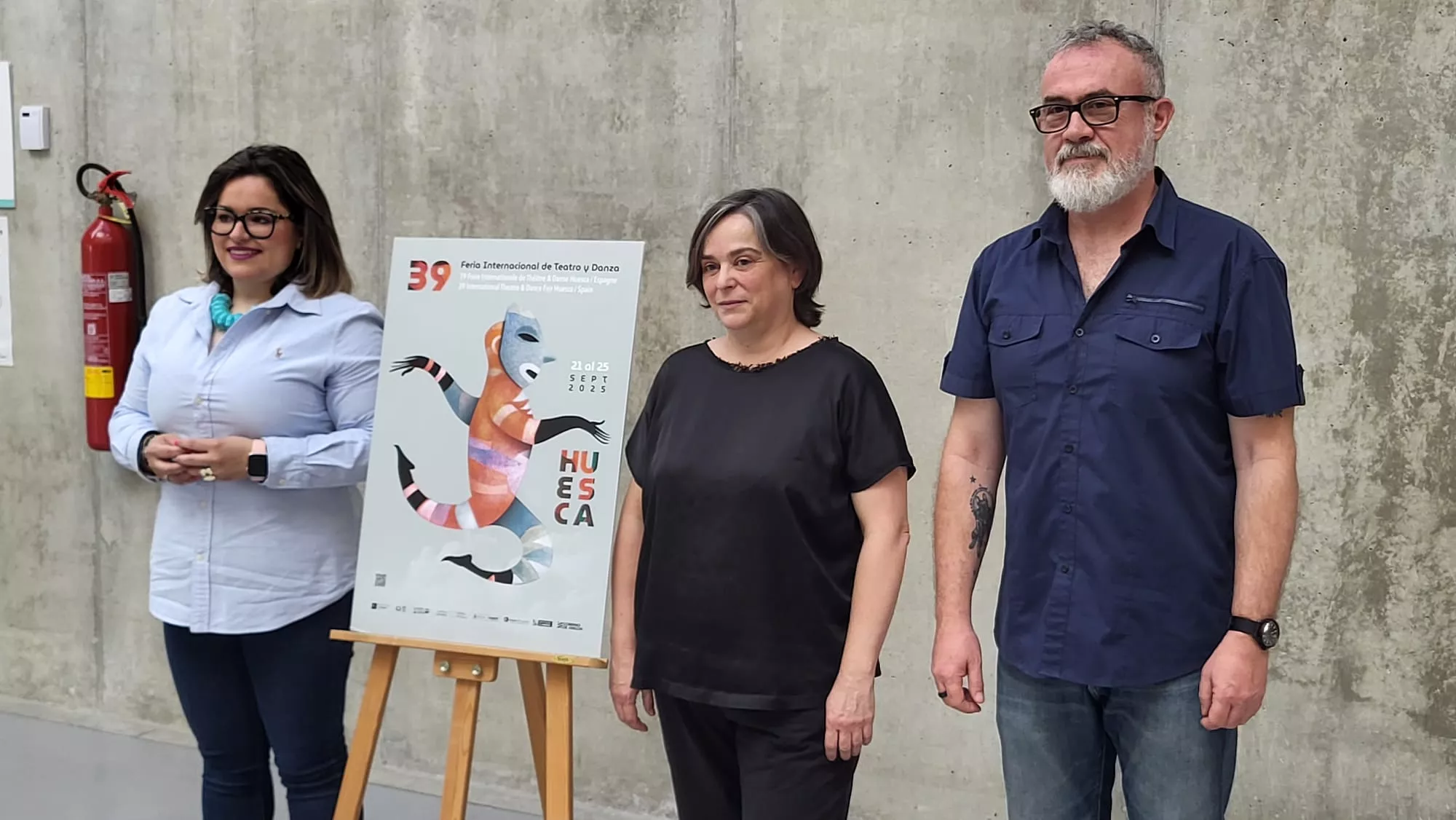Sonia Latre, Pilar Barrio y Lucio Gat junto al cartel de la Feria Internacional de Teatro y Danza de Huesca
