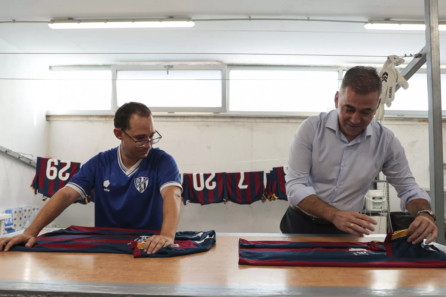 Sergio Raluy y Pablo Lera pliegan unas camisetas de la SD Huesca.