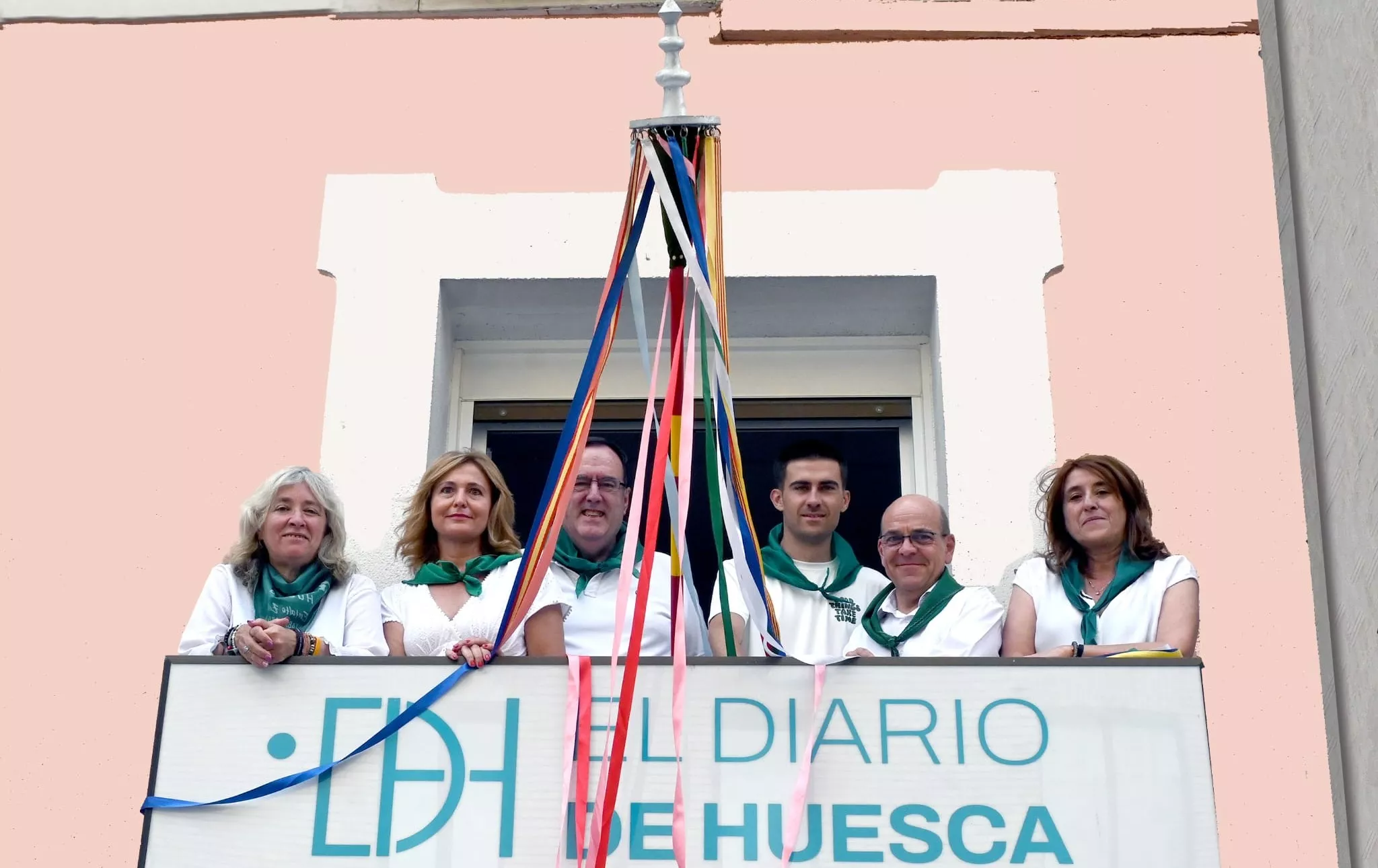 El equipo de EL DIARIO DE HUESCA en el balcón del que cuelga el palo con las cintas.