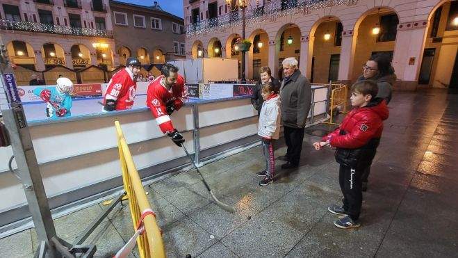 Los jugadores del Club Hielo Jaca explican a una familia cómo manejan el stick