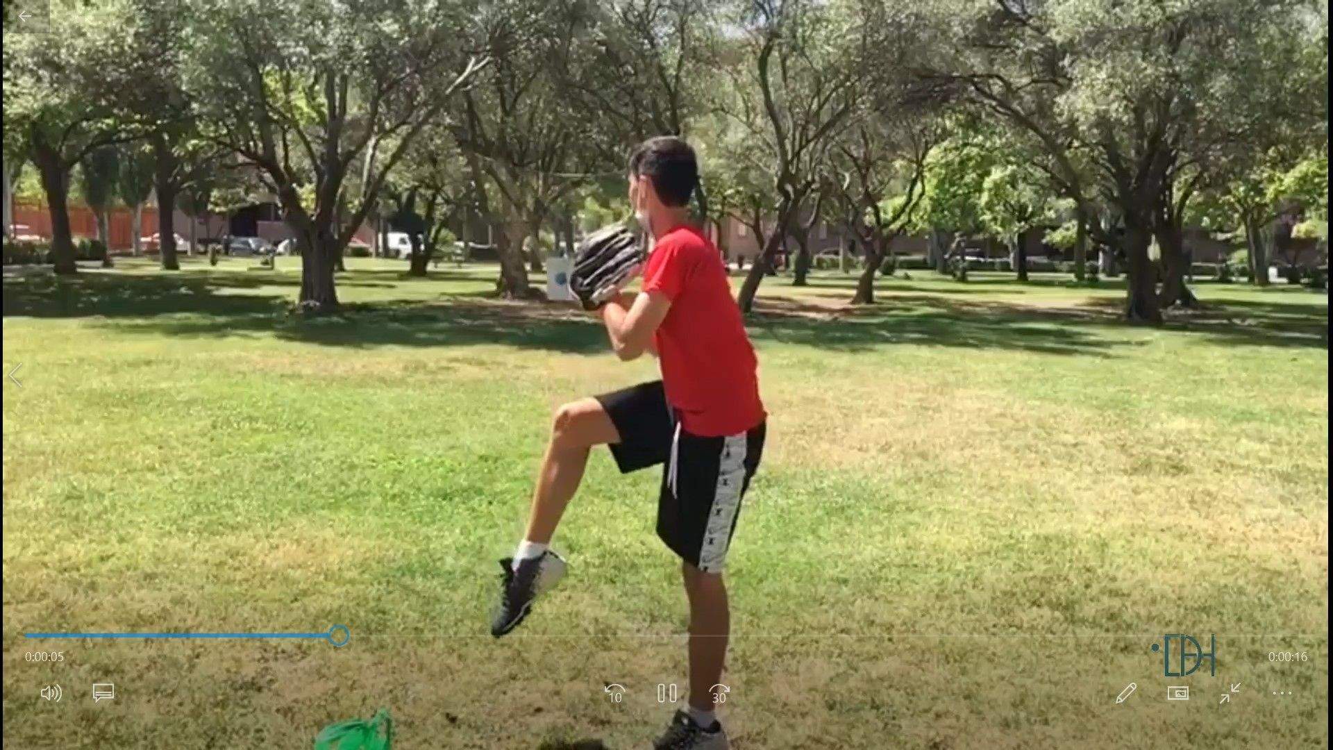 Un joven del Club Béisbol Huesca lanza sobre la malla.