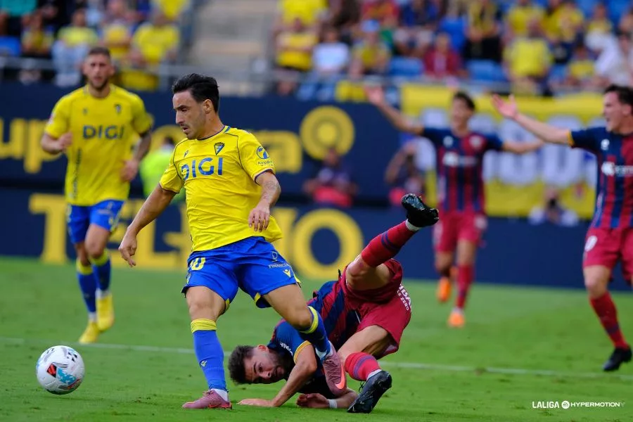 Iza, jugador del Cádiz, derriba a Liberto en el partido ante el Huesca.