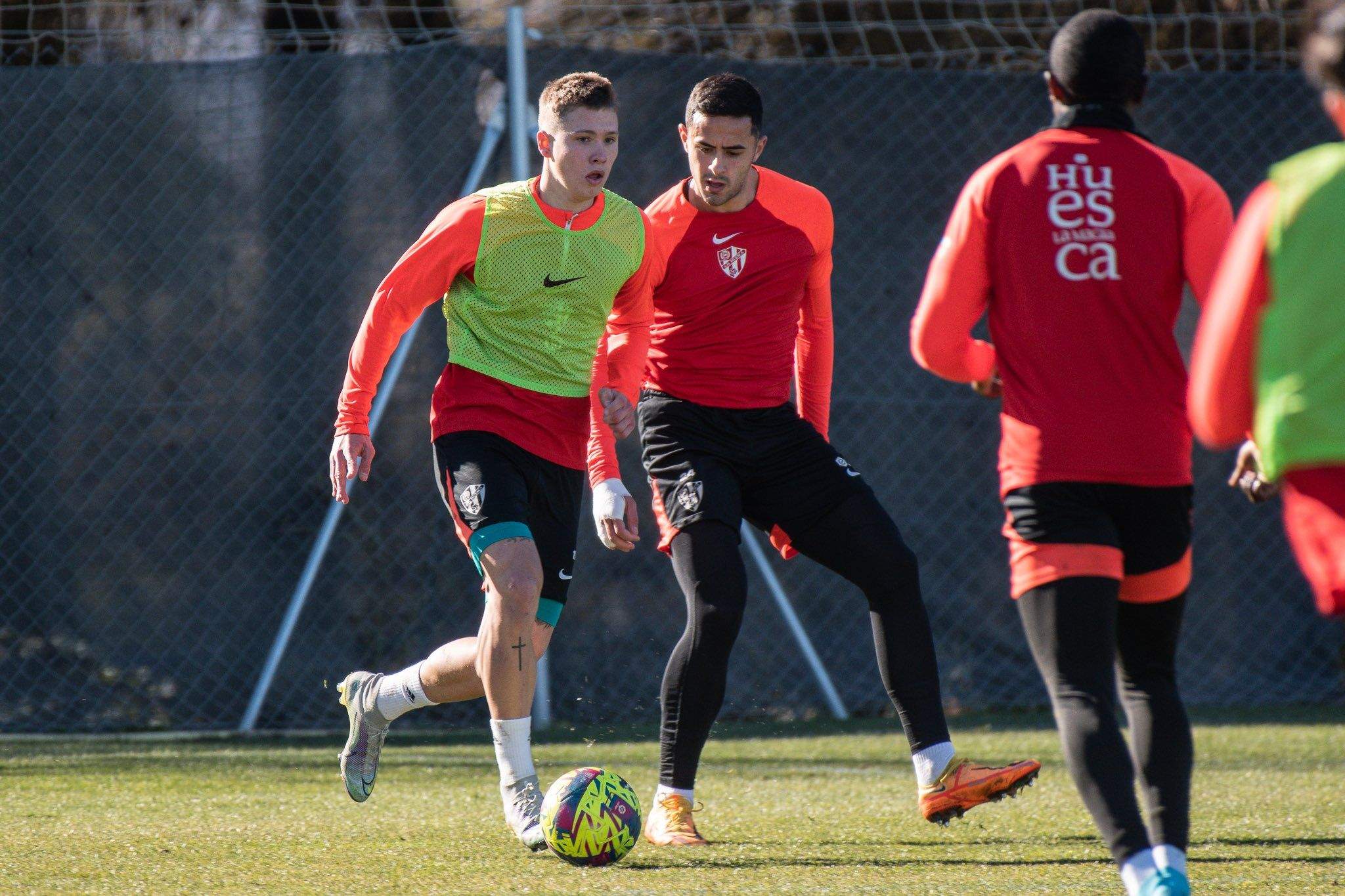 Diego Aznar conduce un balón ante la mirada de Rubén Pulido. Foto: @SDHuesca