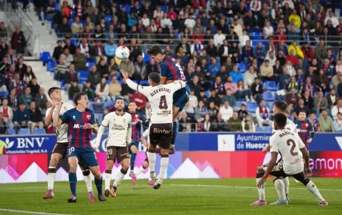 Enol se eleva ante Álex Suárez en el gol del Huesca. Foto: Dani Vidal