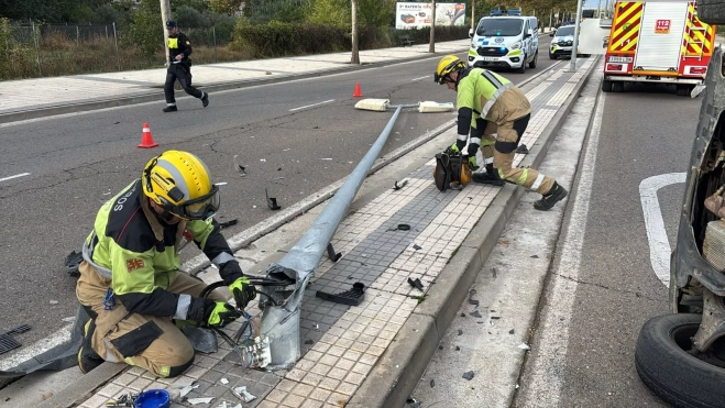 Los bomberos, retirando la farola que había quedado a punto de caer tras el accidente.
