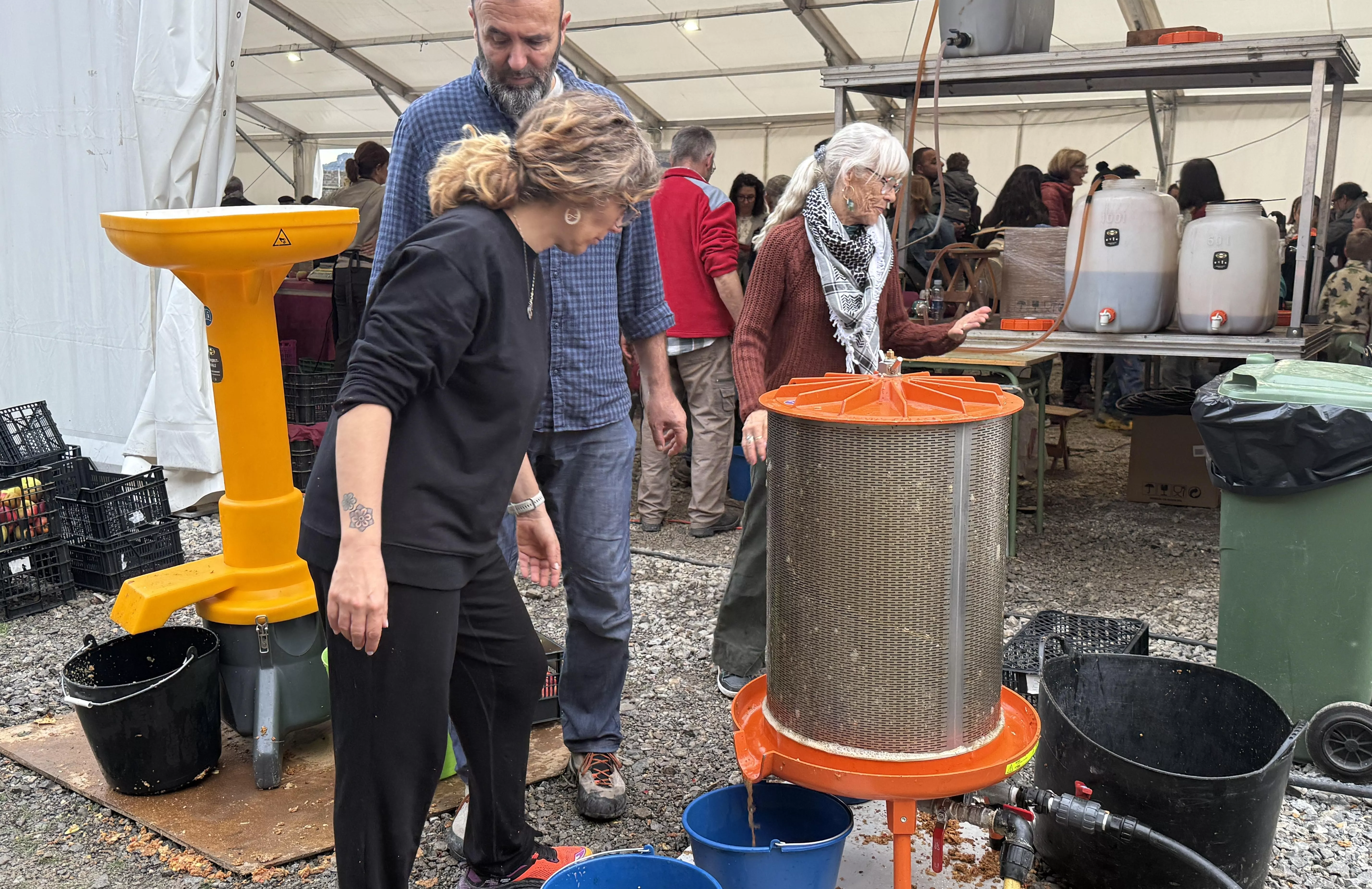 Personas voluntarias en la demostración de producción de zumo de manzana.