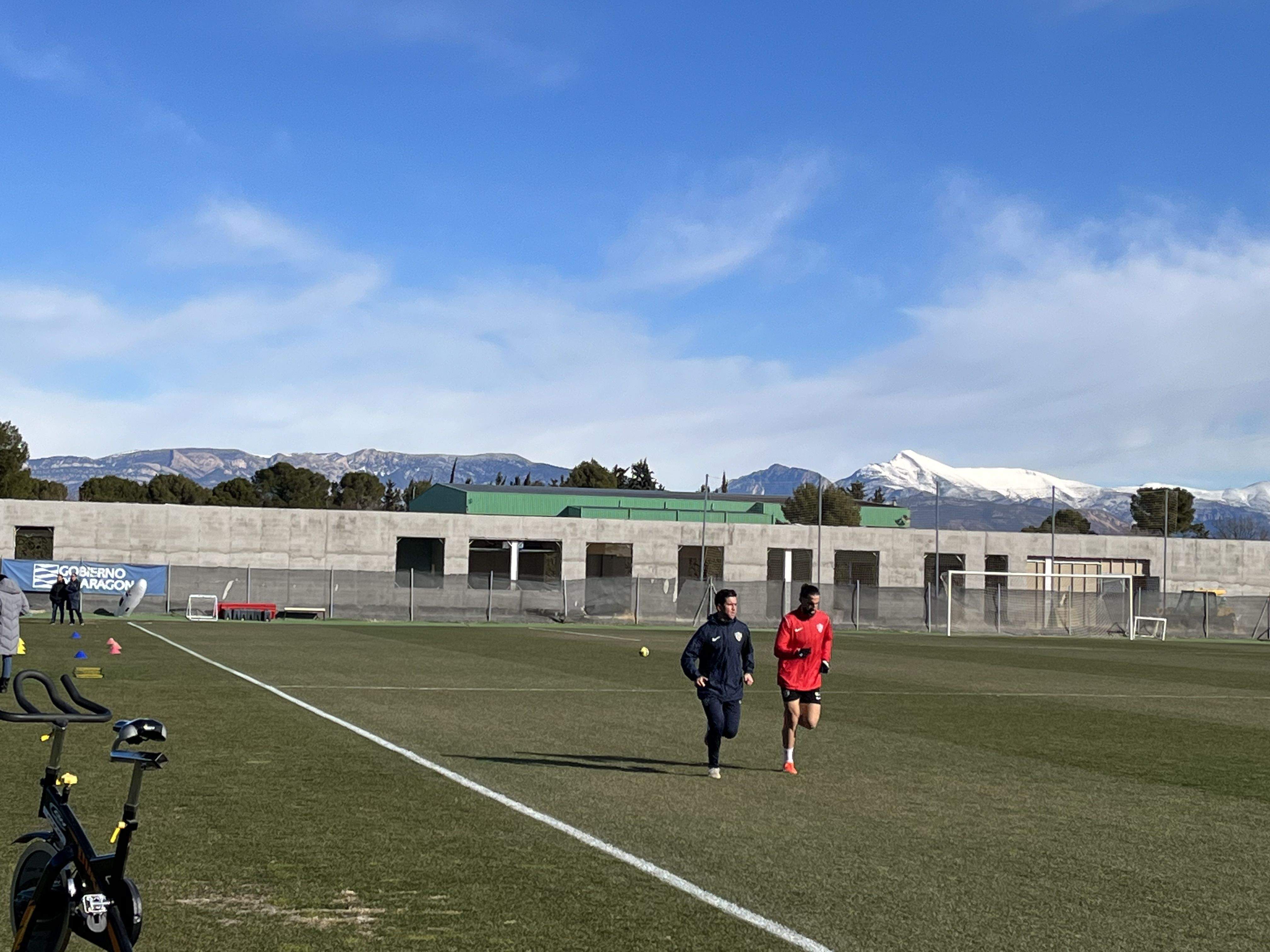 Marc Mateu trota sobre el césped del IES Pirámide junto al readaptador Carlos Calvo. Foto: A. Mora