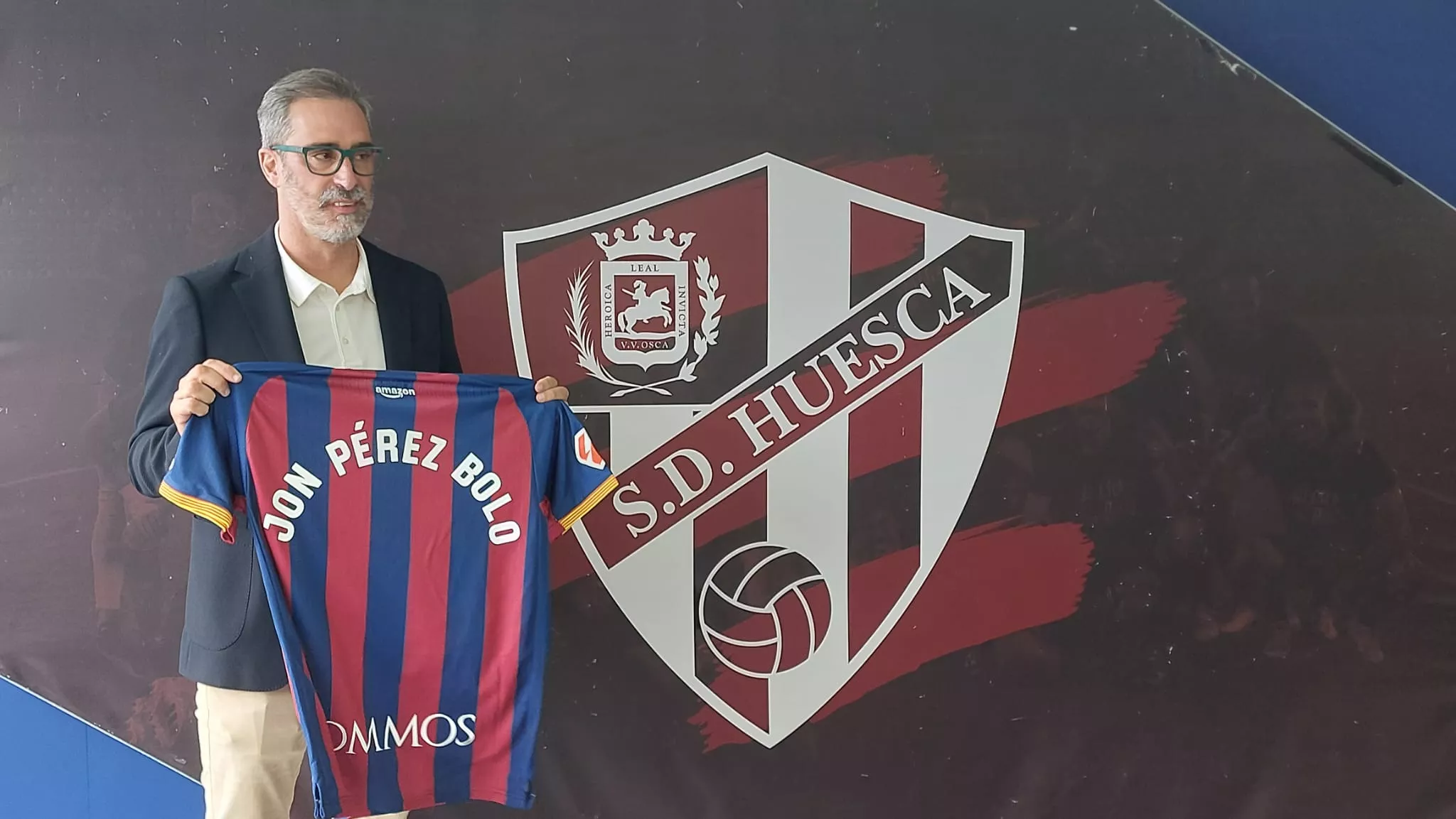 Jon Pérez Bolo, entrenador del Huesca junto al escudo