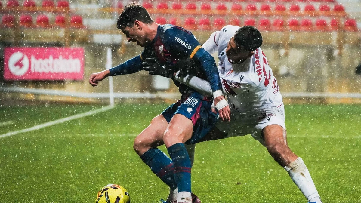 Enol pugna con un jugador de la Leonesa. Foto: SD Huesca.
